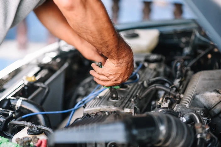 Atelier de carrosserie automobile, technicien utilisant une meuleuse d'angle sur carrosserie de véhicule blanc
