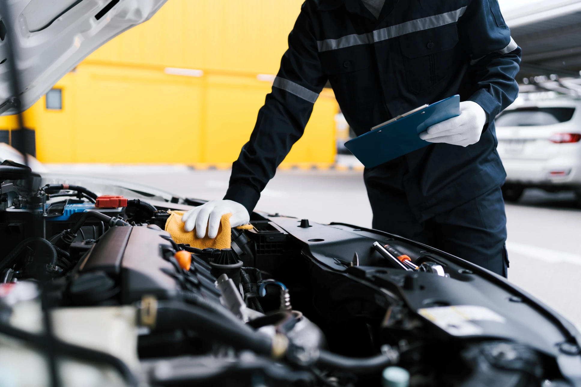Réparateur mécanicien automobile vérifiant un moteur de voiture en inspectant et en écrivant au presse-papiers la liste de contrôle pour la réparation des machines et le service de voiture pour le concept de vérification de l'entretien et de l'entretien