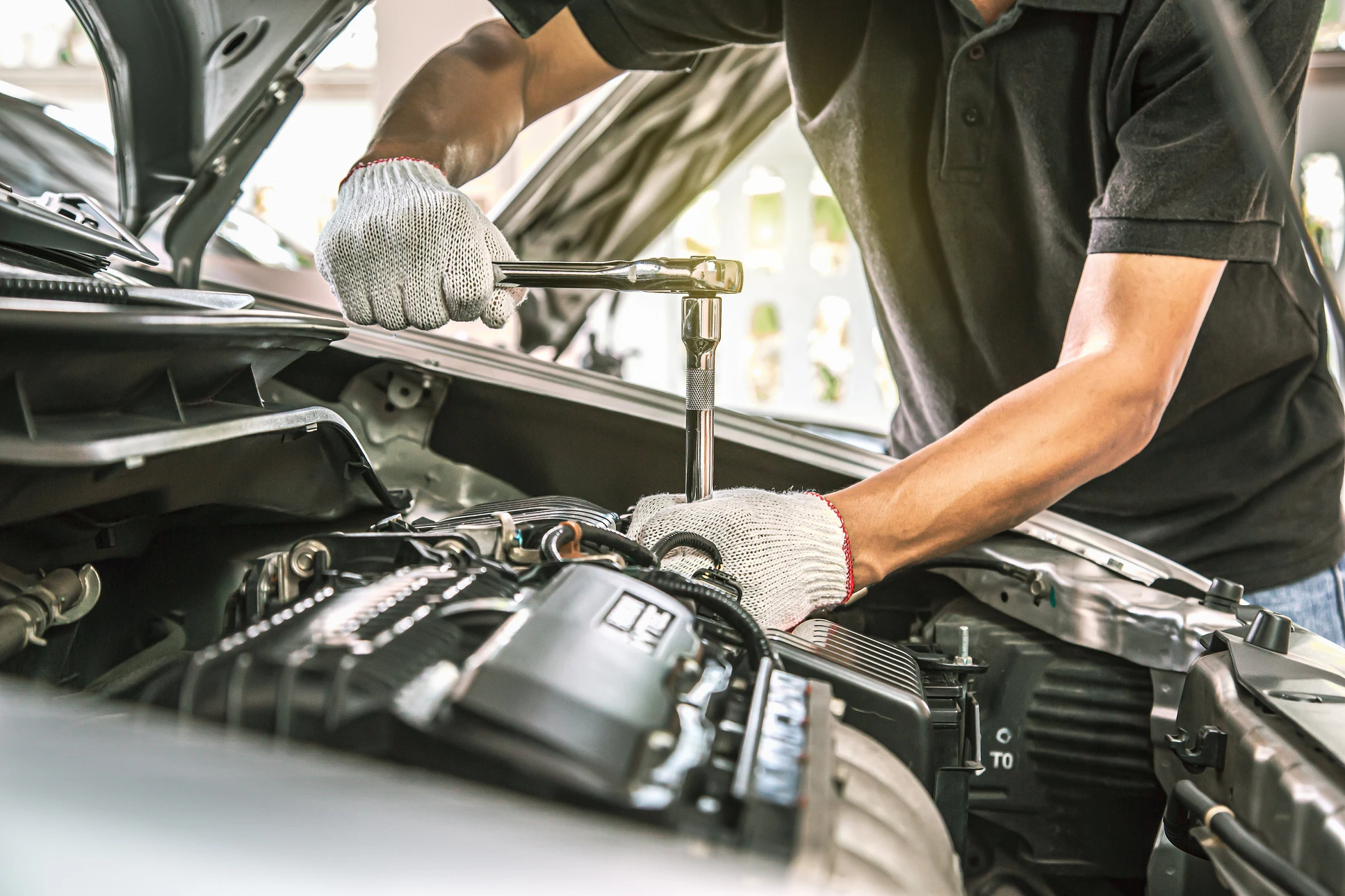Mécanicien automobile travaillant sous véhicule surélevé dans garage professionnel