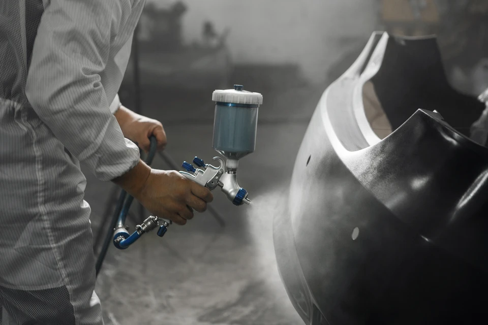Atelier de detailing automobile en intérieur, professionnel utilisant une polisseuse rotative électrique sur capot noir brillant d'un véhicule