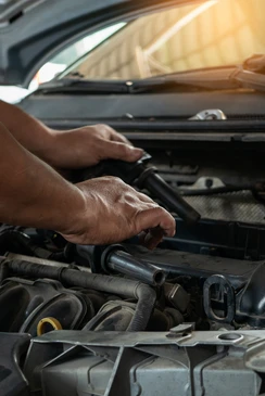 Atelier de réparation automobile avec deux mécaniciens travaillant sous un véhicule surélevé
